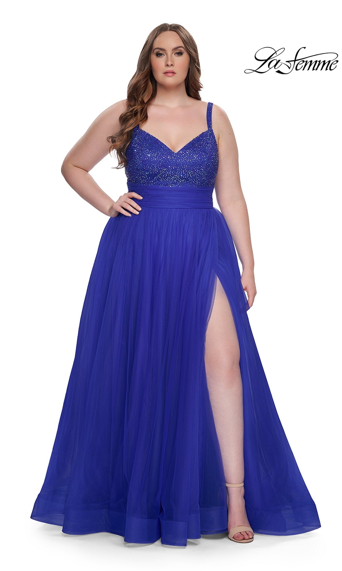 A woman models the La Femme Long Prom Dress 31251 in royal blue, featuring a plus-size fit, beaded bodice, tulle skirt, and high side slit. The La Femme logo is displayed in the top right corner.